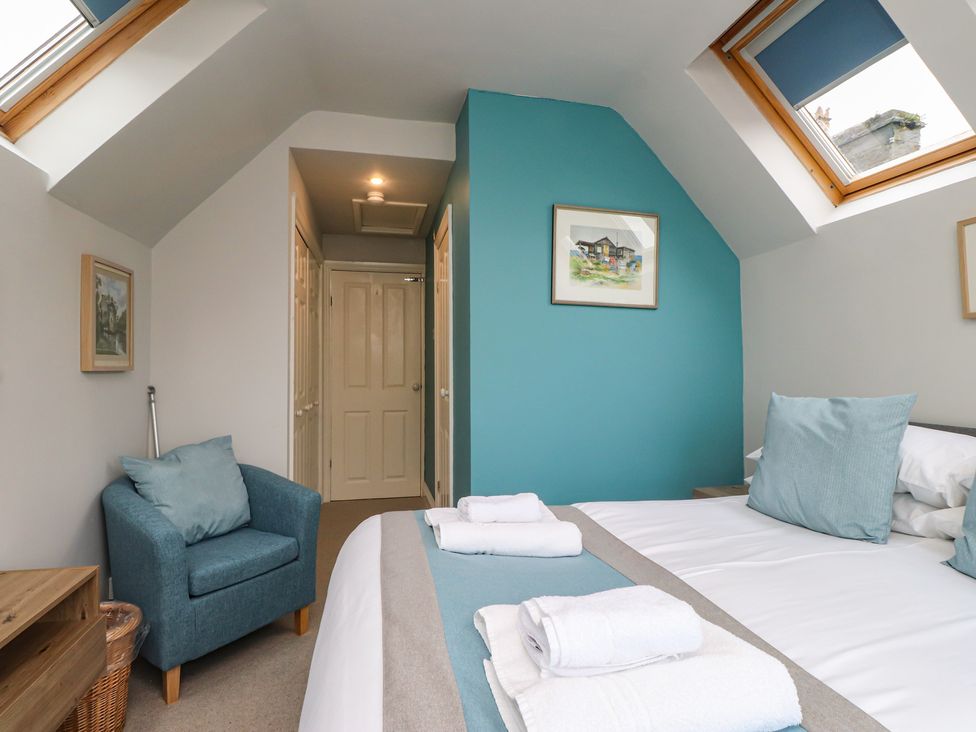 A bedroom with a bed and blue chair at Alltwen in Borth-y-Gest