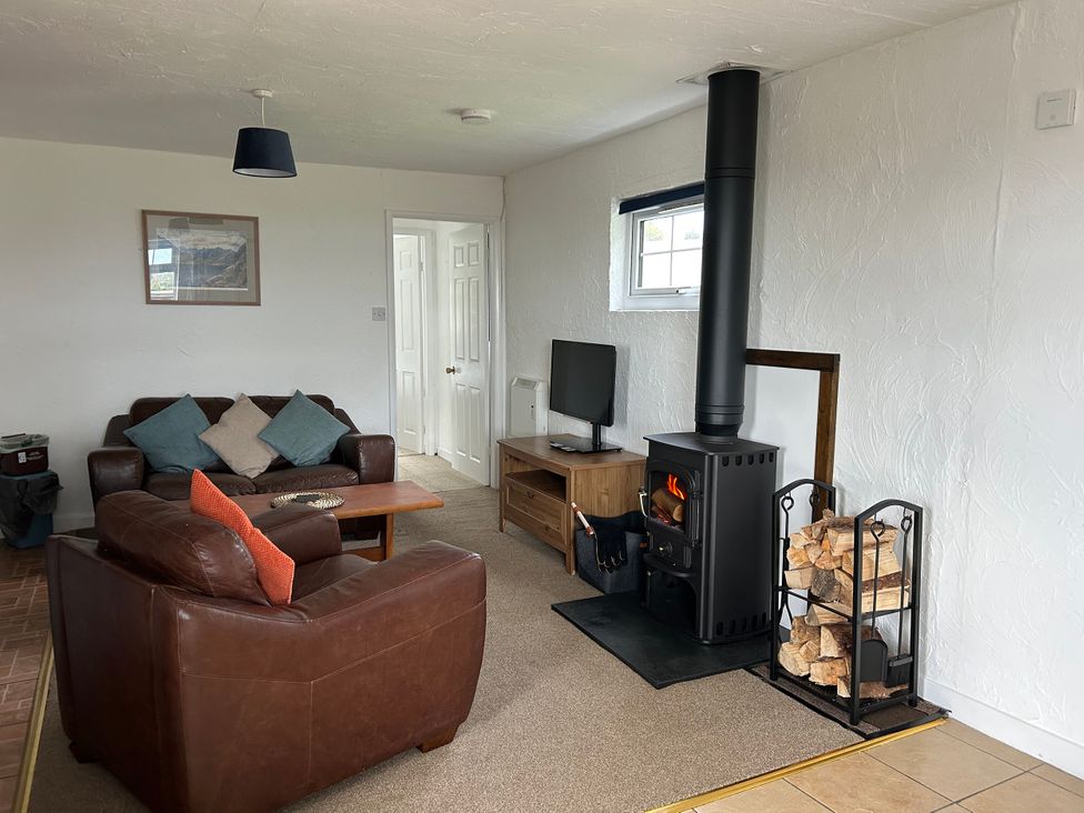A living room with a sofa and wood stove at Min Y Mor Llanystumdwy near Criccieth