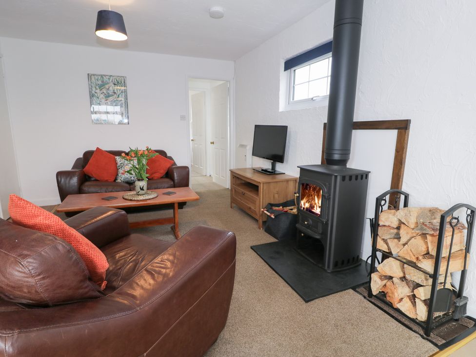 A living room with a sofa and a wood burning stove at Min Y Mor Llanystumdwy near Criccieth