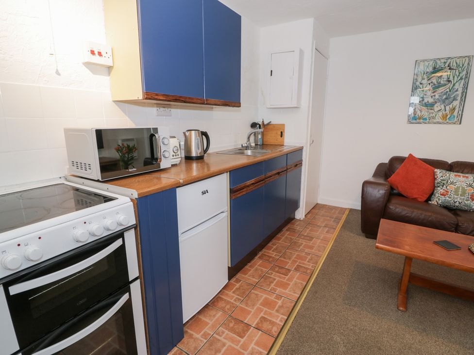 A kitchen with a stove and refrigerator at Min Y Mor Llanystumdwy near Criccieth
