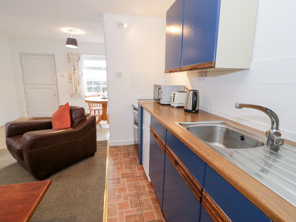A kitchen with appliances and seating area at Min Y Mor in Llanystumdwy near Criccieth