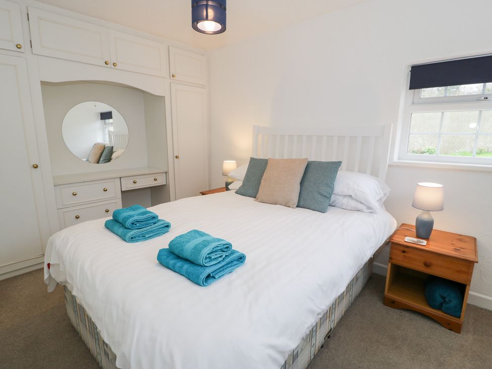 A bedroom with a bed and wardrobe at Min Y Mor in Llanystumdwy near Criccieth