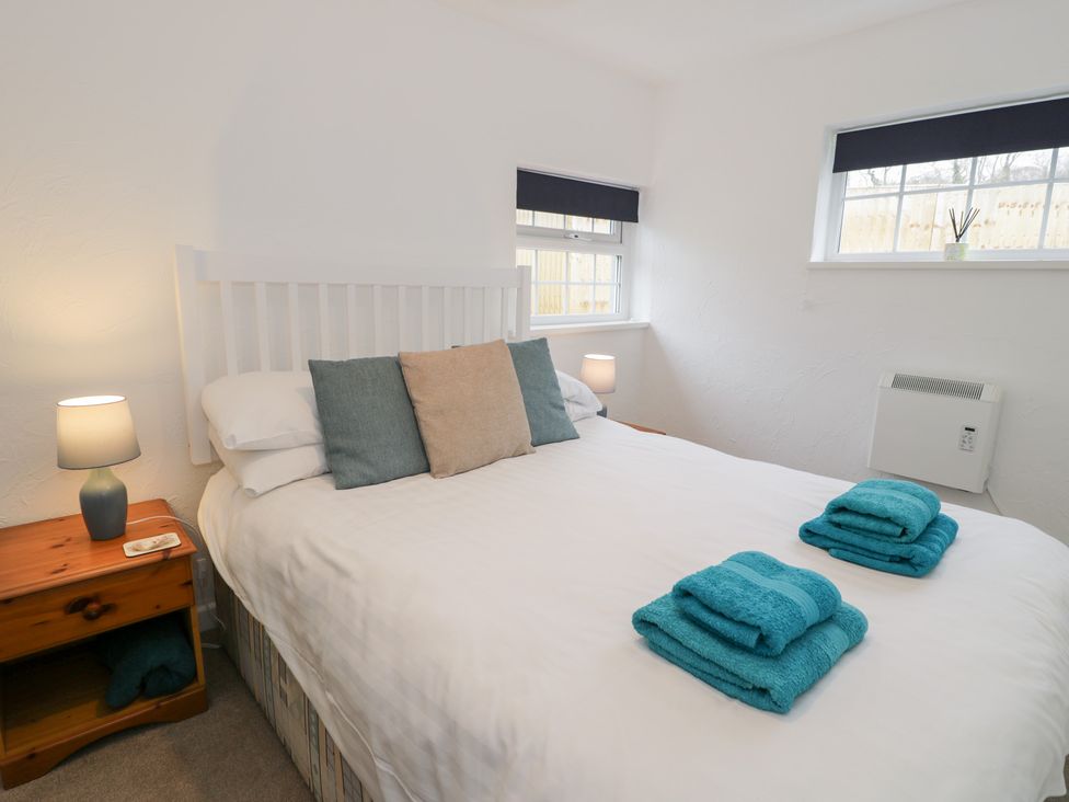 A bedroom with a bed, lamp, and towels at Min Y Mor in Llanystumdwy near Criccieth