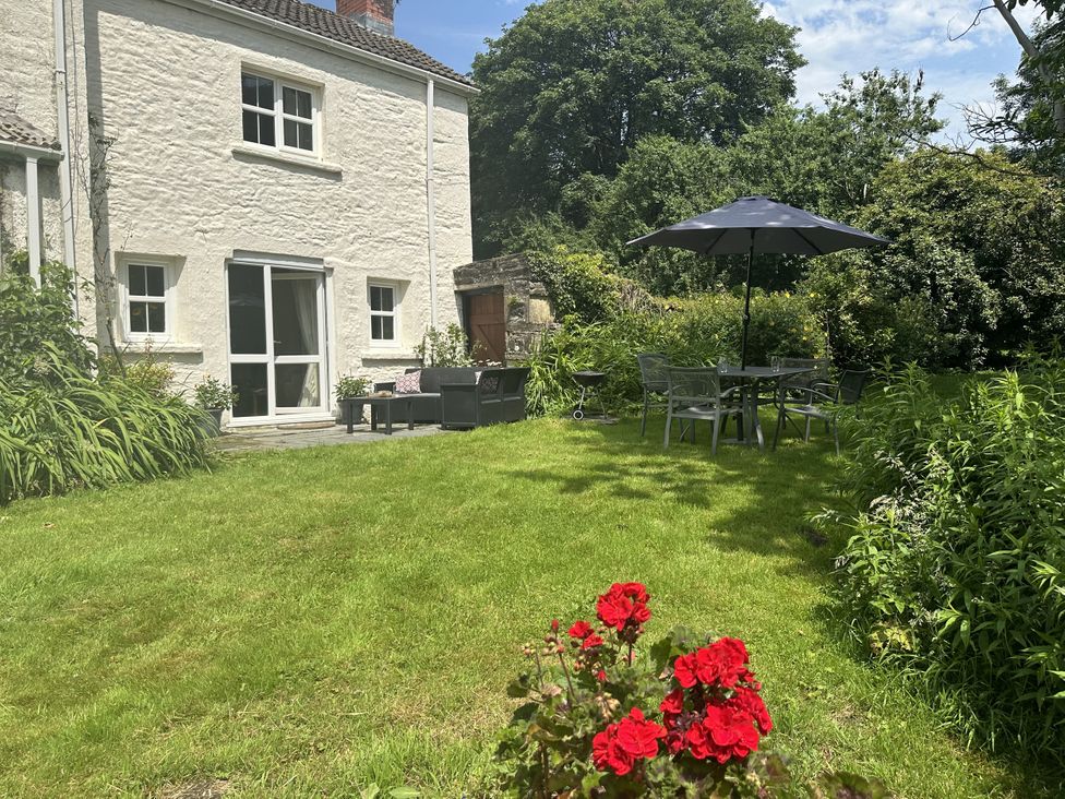 A garden with seating and an umbrella at Parke Cottage in Henllan Amgoed near Whitland