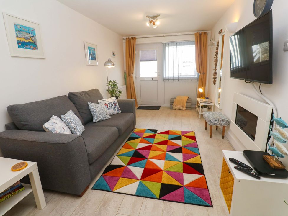 A living room with a sofa and rug at Driftwood in Marazion