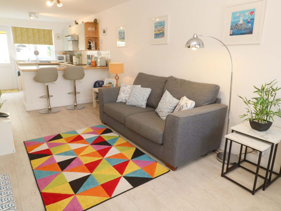 A living room with a sofa and colorful rug at Driftwood in Marazion