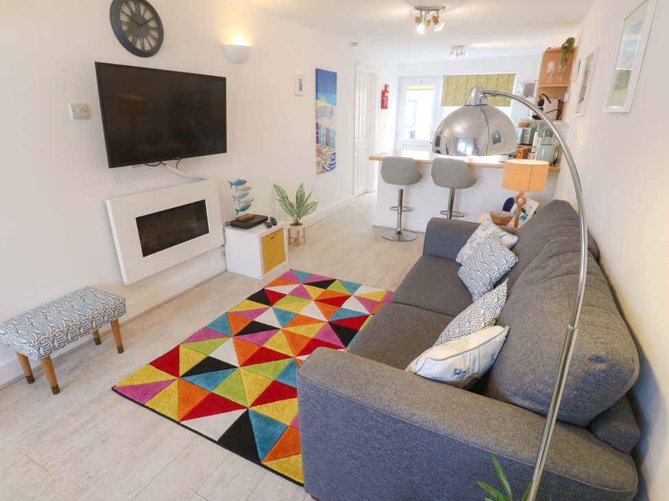 A living room with a television and sofa at Driftwood in Marazion