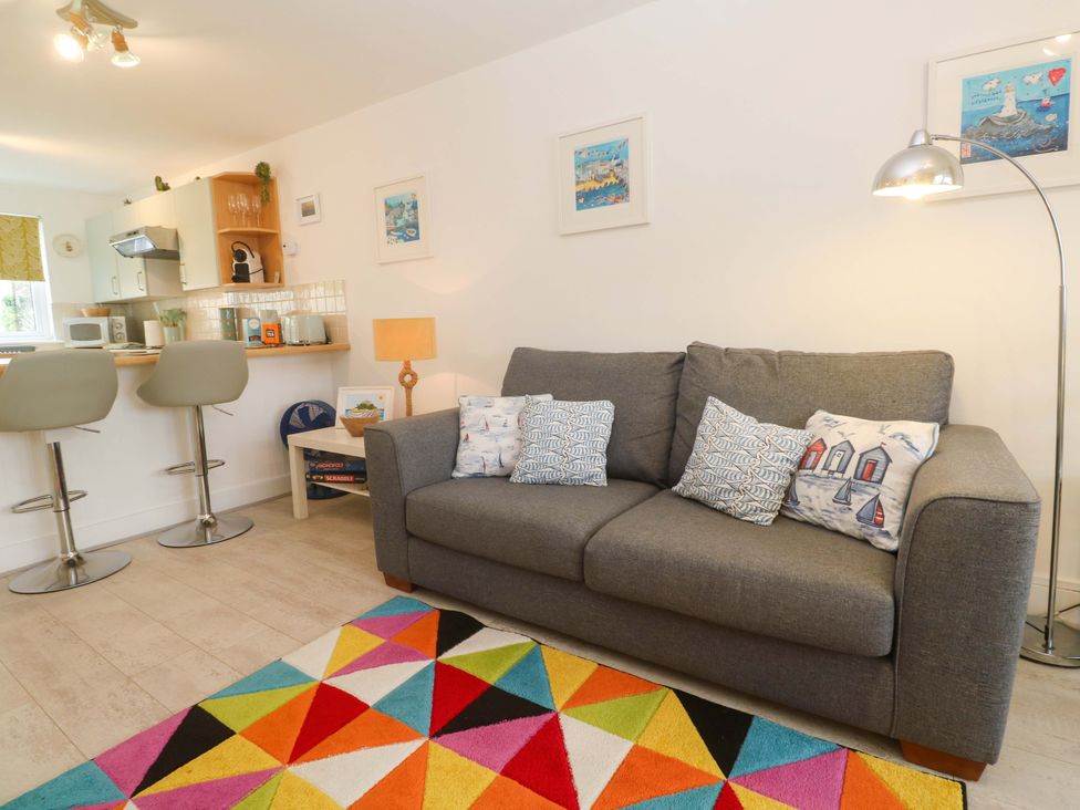 A living room with a sofa and bar stools at Driftwood in Marazion