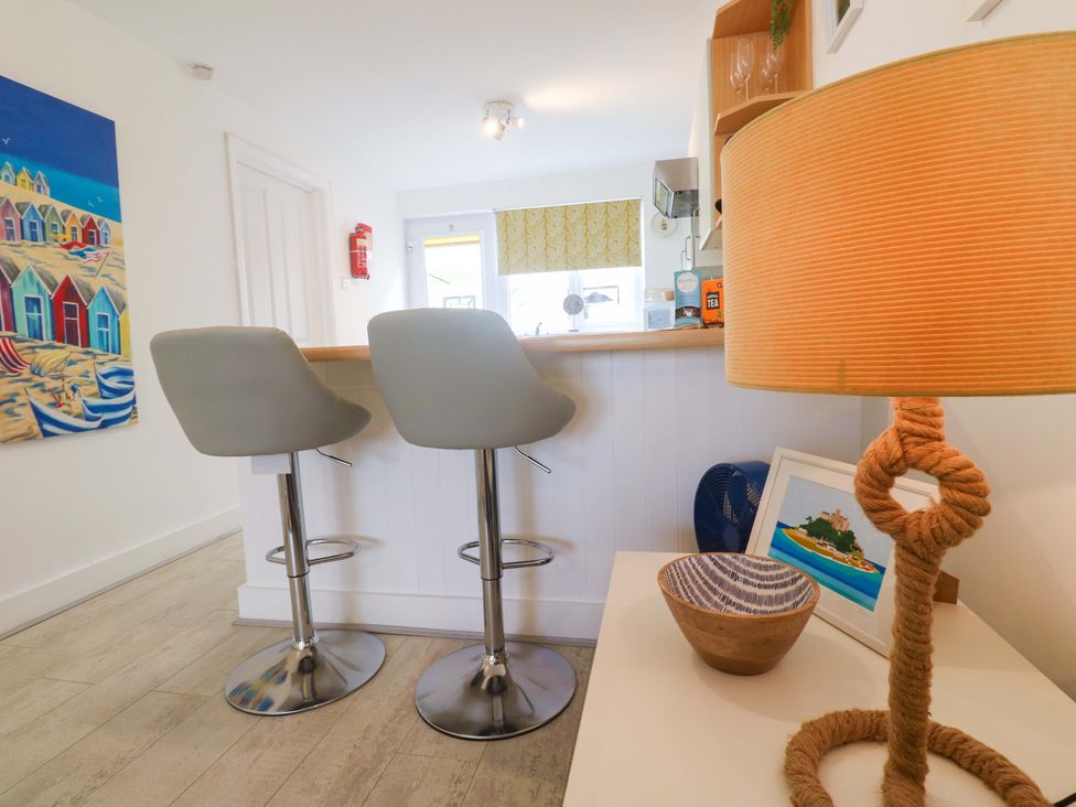 A kitchen with bar stools and a lamp at Driftwood in Marazion