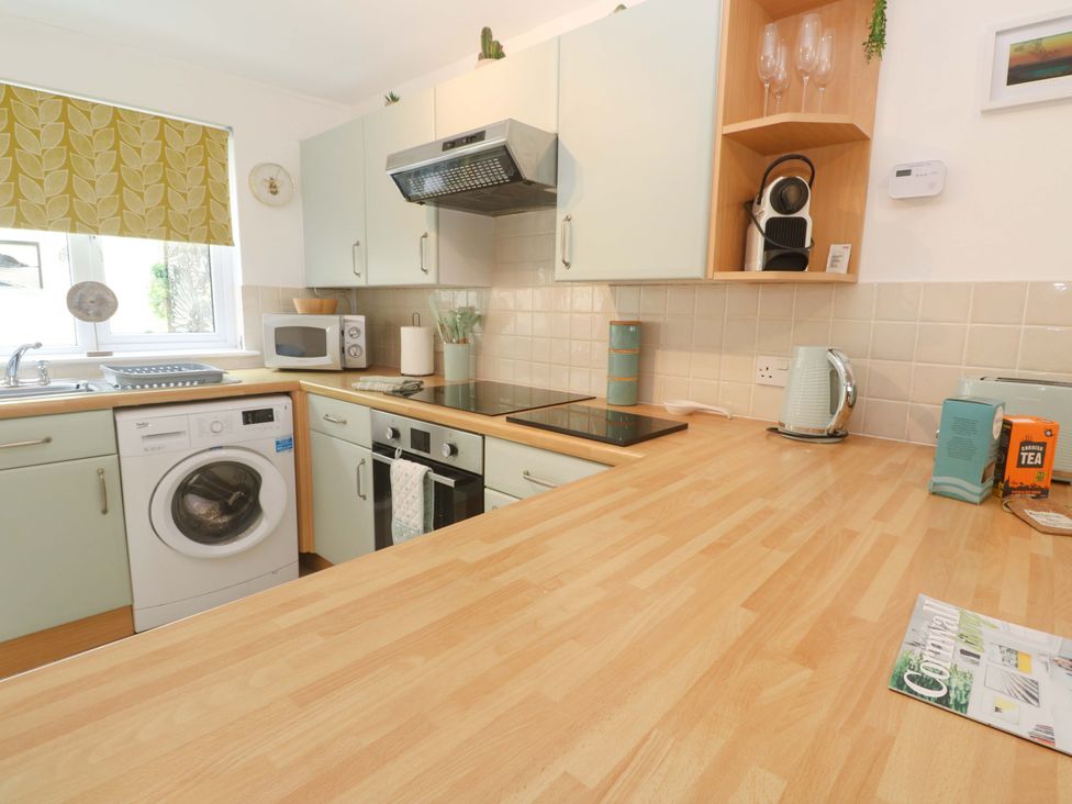 A kitchen with a washing machine and microwave at Driftwood in Marazion