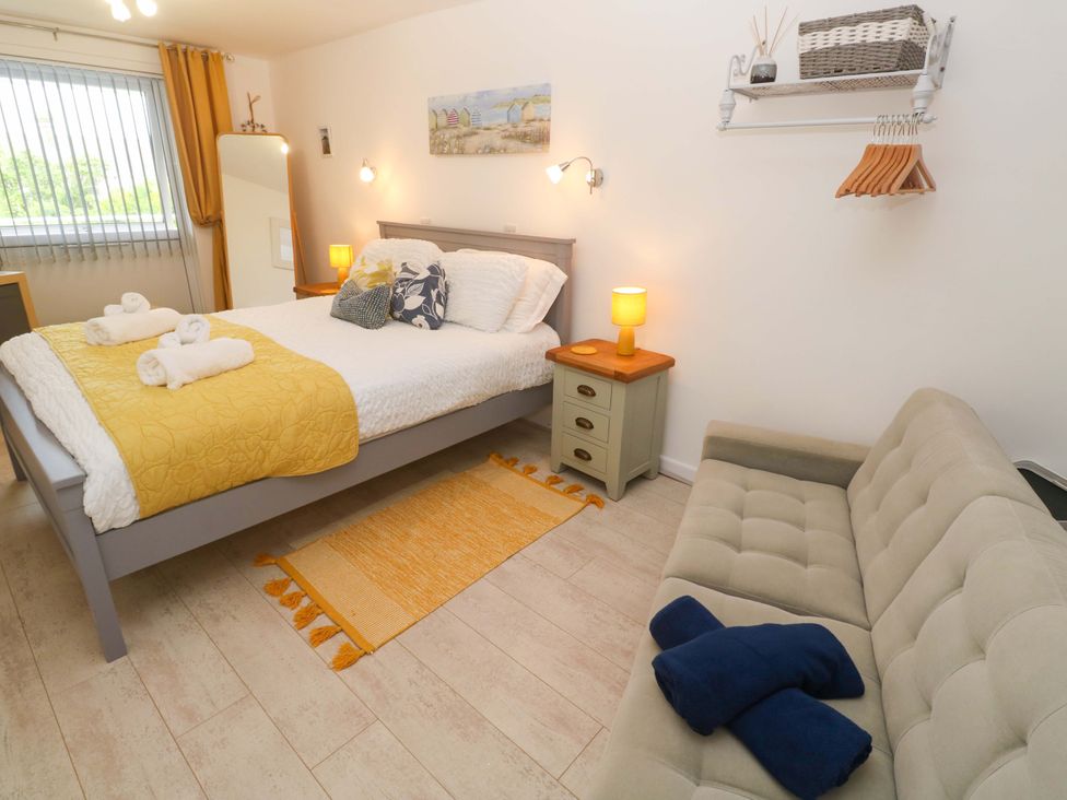 A bedroom with a bed and a sofa at Driftwood in Marazion