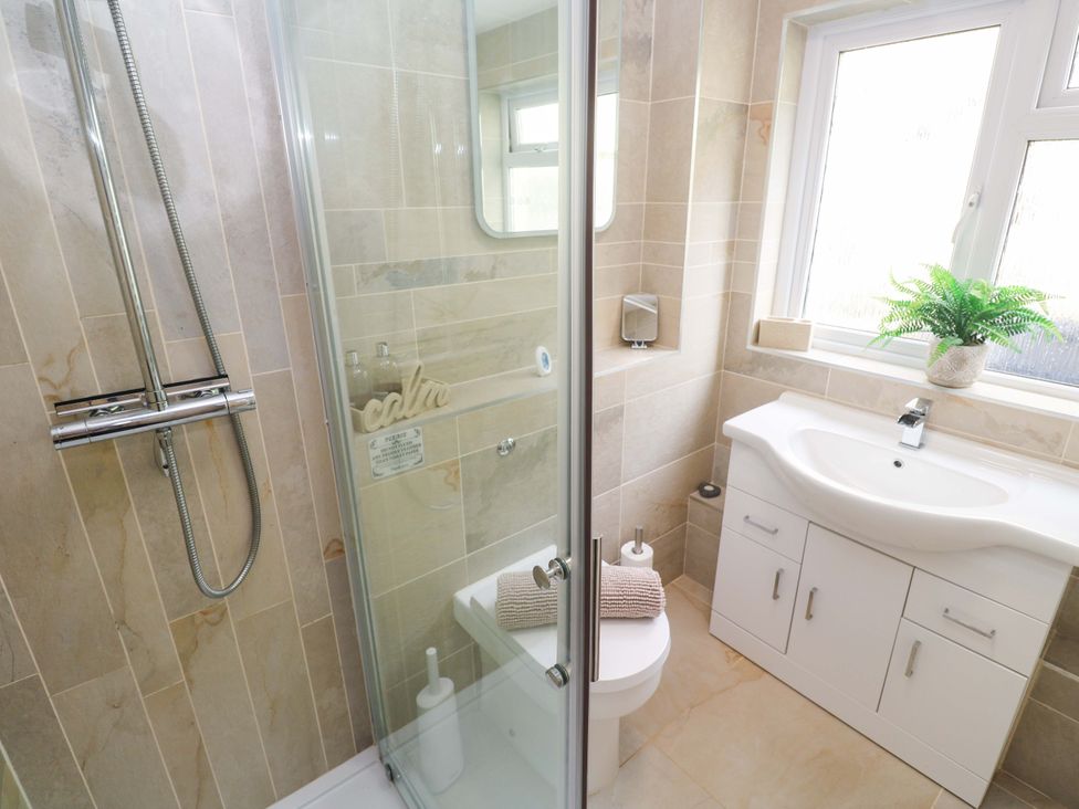 A bathroom with a shower, toilet, and sink at Driftwood in Marazion