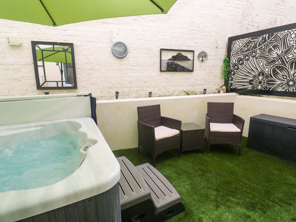 An outdoor area with a hot tub and seating at Driftwood in Marazion