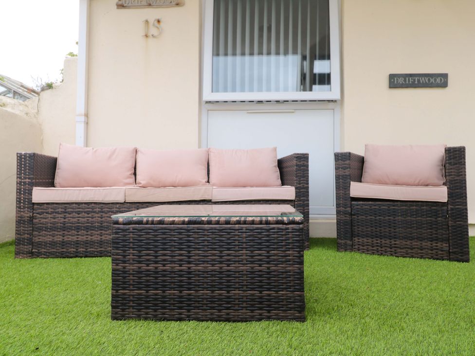 An outdoor seating area with a sofa and armchairs at Driftwood in Marazion