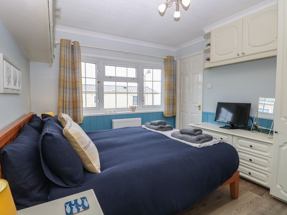 A bedroom with a bed and television at Seaward in Trimingham