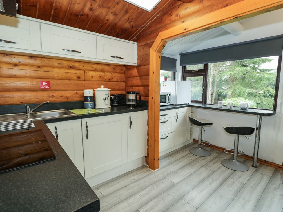 A kitchen with cabinets, sink, and bar stools at Babbling Brook near Blaenau Ffestiniog