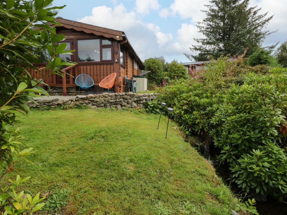 An outdoor area with a wooden cabin and seating at Babbling Brook near Blaenau Ffestiniog