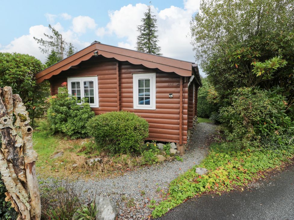 A wooden cabin with a gravel path and bushes at Babbling Brook in Bron Aber near Blaenau Ffestiniog