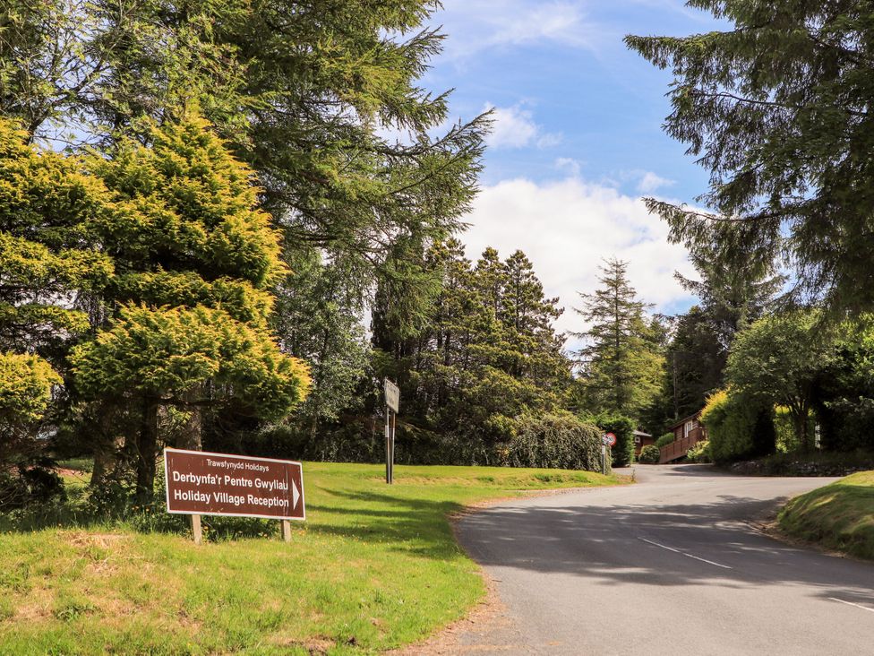 A road with trees and a sign pointing to the holiday village reception at Babbling Brook in Bron Aber near Blaenau Ffestiniog