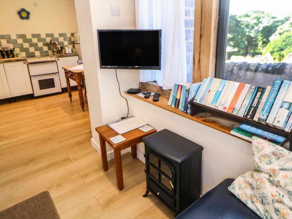A kitchen with a television, table, and bookshelf filled with books at The Netty in Flash