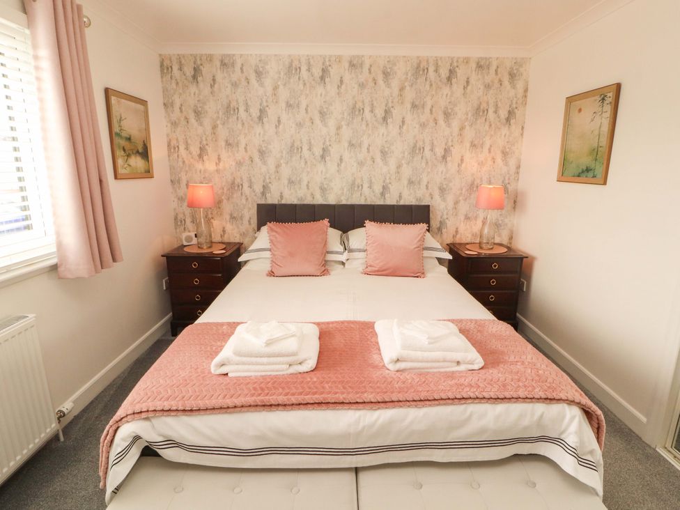 A bedroom with a bed, bedside tables and lamps at The Paddock in Kirkcowan