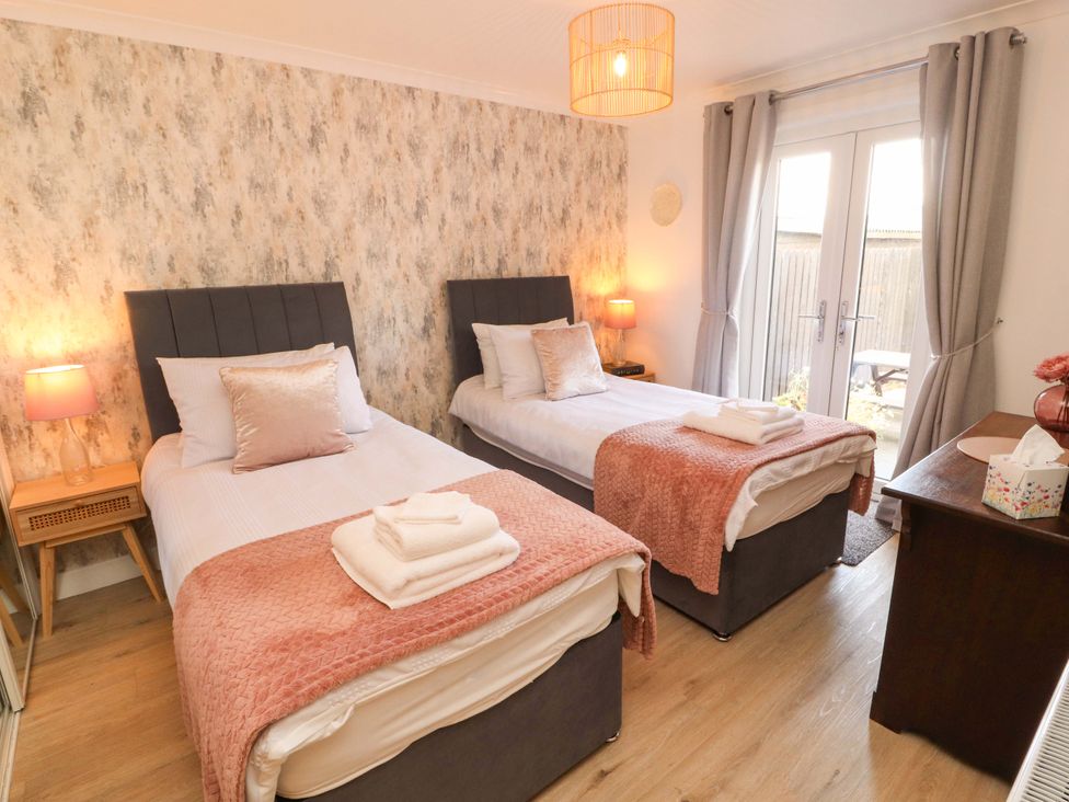 A bedroom with two beds and a bedside table at The Paddock in Kirkcowan