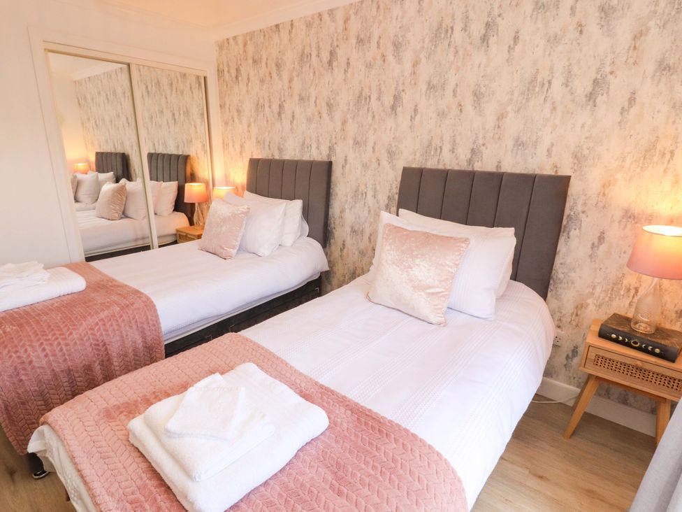 A bedroom with twin beds and a mirror at The Paddock in Kirkcowan