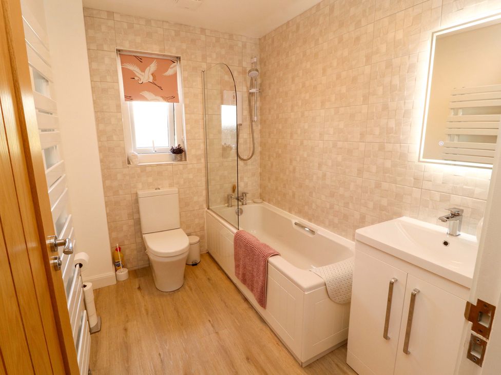 A bathroom with a bathtub, toilet, sink and window at The Paddock in Kirkcowan