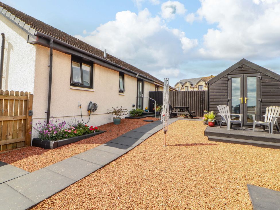 A garden with flower beds and seating area at The Paddock in Kirkcowan
