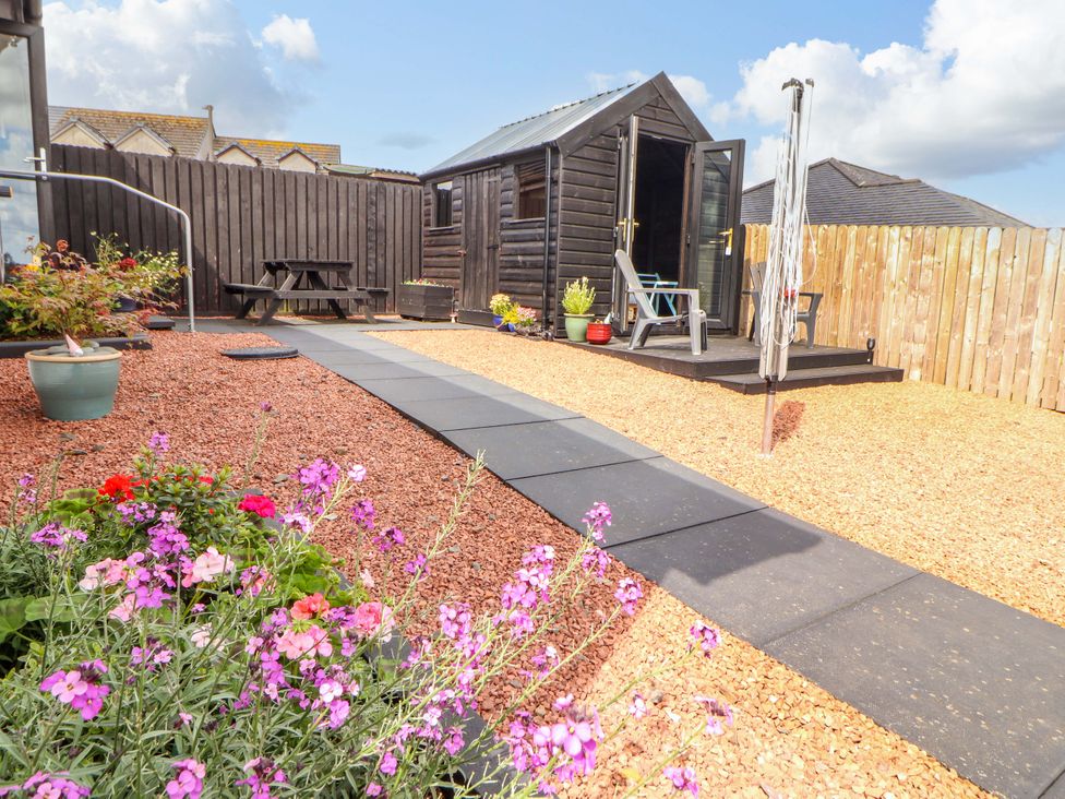 A garden with a shed and flowers at The Paddock in Kirkcowan
