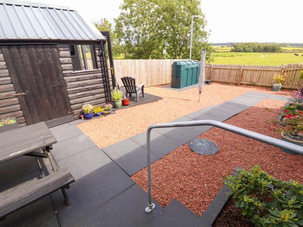 A garden with gravel area, table, shed, and recycling bins at The Paddock in Kirkcowan