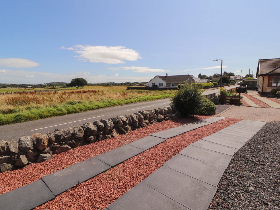 A view of a house and road with grass and stone wall at The Paddock in Kirkcowan