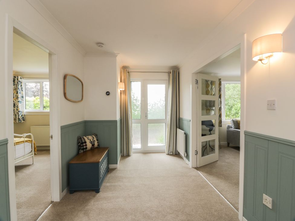 A hallway with a bench and door leading to a garden at The Rowans in 