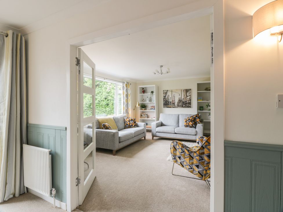 A living room with sofas, an armchair and a shelving unit at The Rowans in 