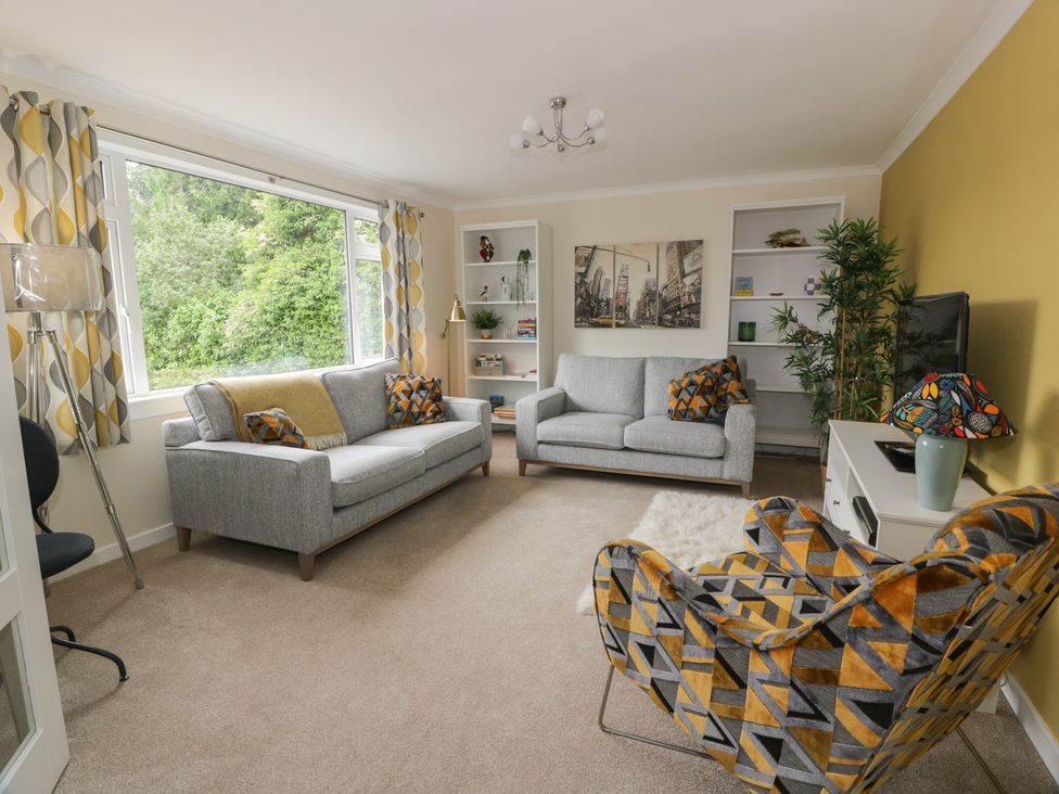 A living room with a gray sofa and patterned armchair at The Rowans in 