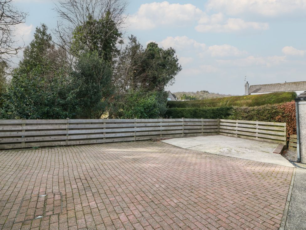 A paved outdoor area with a wooden fence and trees at The Rowans 