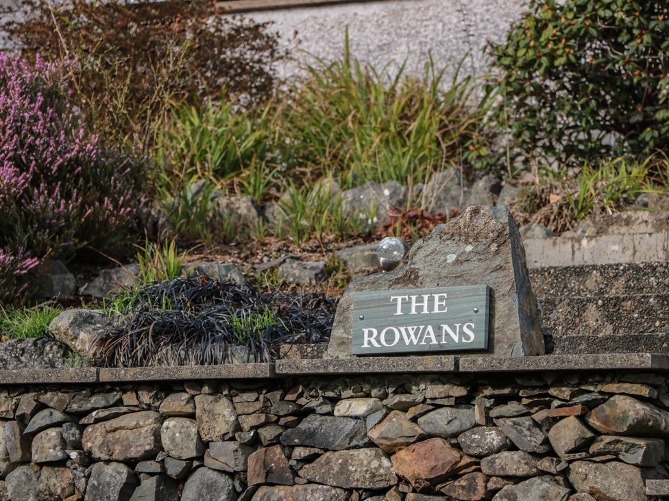 A stone sign reading The Rowans surrounded by plants at The Rowans in 