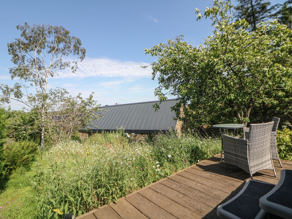 A garden with a table and chairs at Overlea Coach House in Hayfield