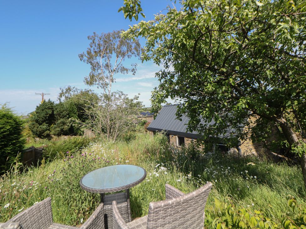 A garden with a table and chairs at Overlea Coach House Hayfield