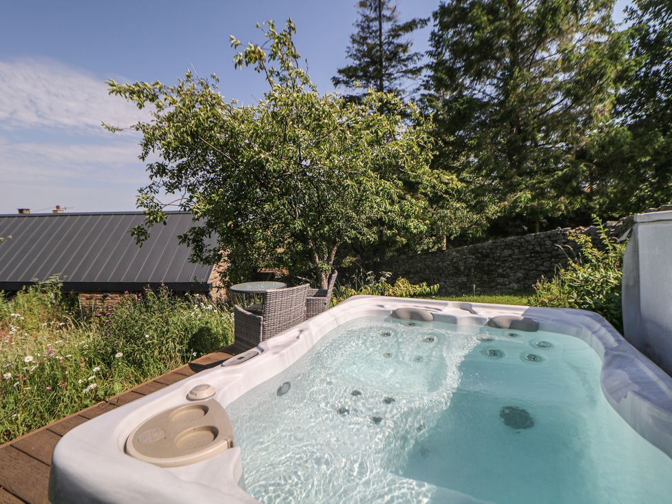 A hot tub with surrounding greenery at Overlea Coach House in Hayfield