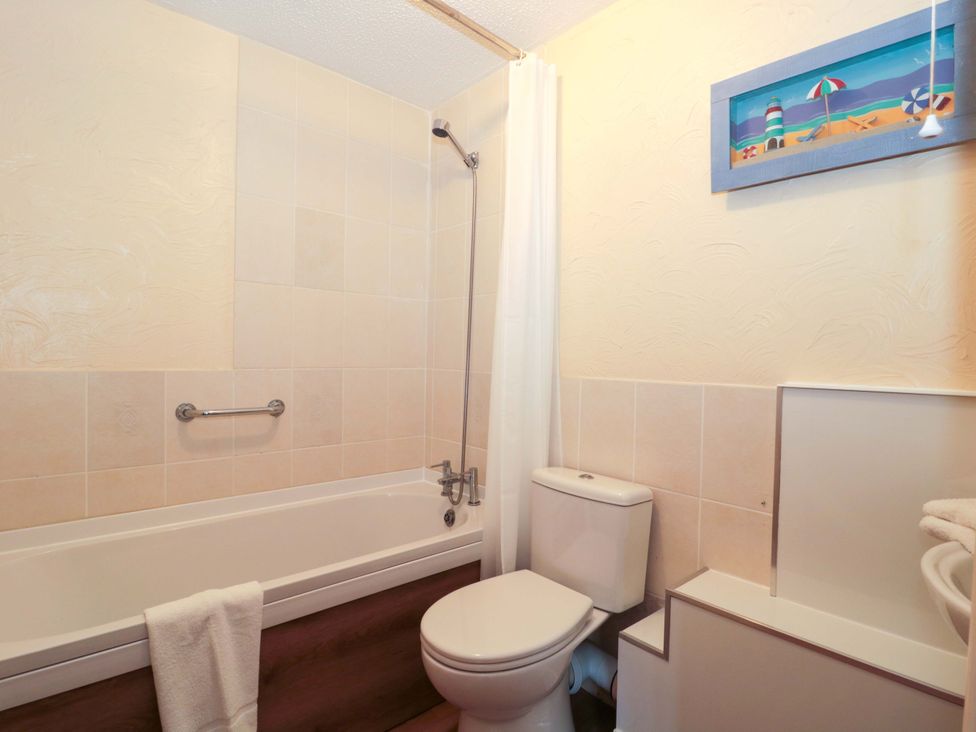 A bathroom with a bathtub, toilet, and shower at Owls Retreat in Brean