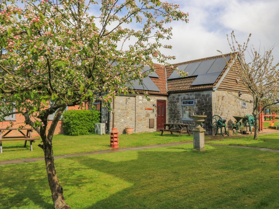 A house with trees and benches in the garden at Carthouse Brean