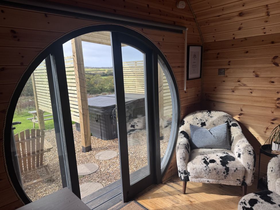 A living room with a round door and chair at Stargaze in Ponsanooth