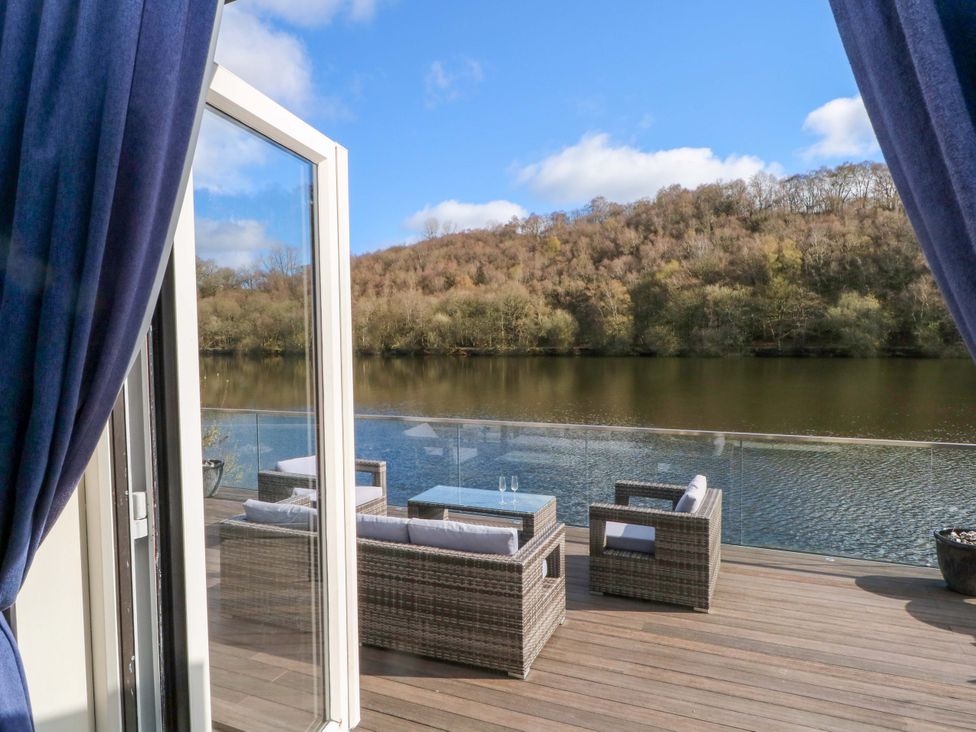 An outdoor area with a seating arrangement overlooking a lake at The Bothy in Leek