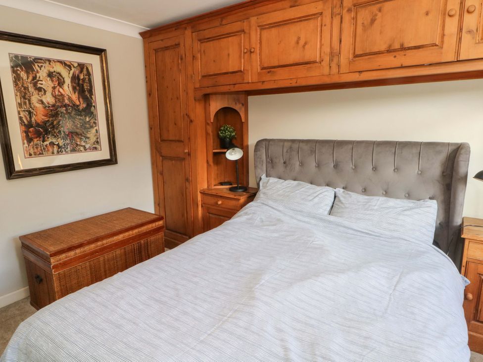 A bedroom with a bed and wooden storage at The Bothy in Leek