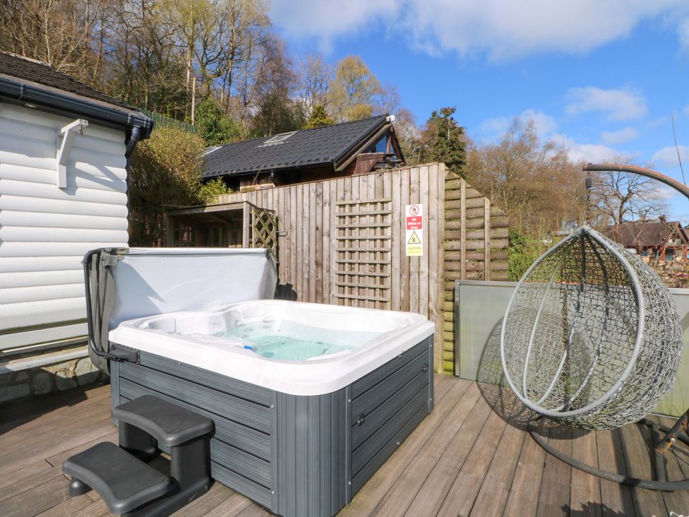An outdoor area with a hot tub and a hanging chair at The Bothy in Leek