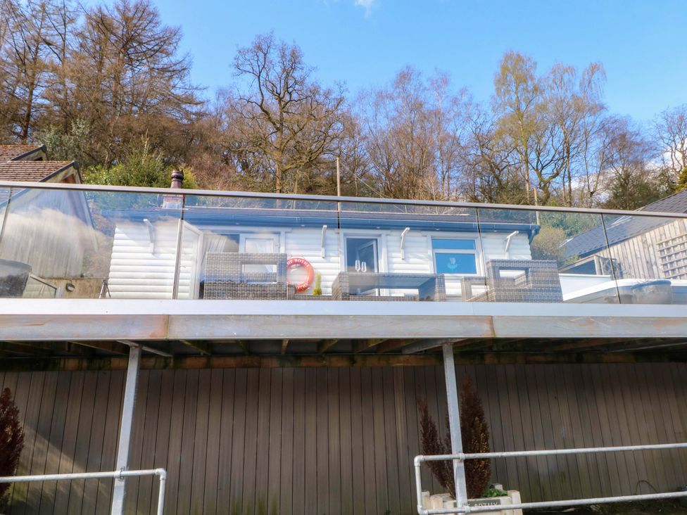 A cabin with a deck and glass railing at The Bothy in Leek