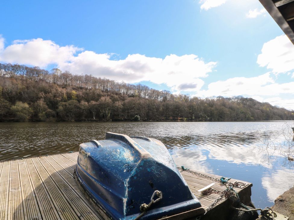 A boat on a dock with water and trees in the background at The Bothy in Leek