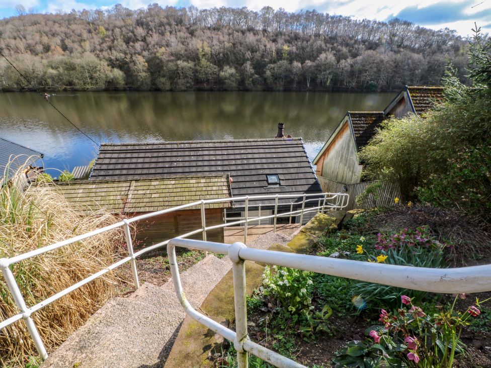 A view of steps leading down to a lake with buildings nearby at The Bothy in Leek