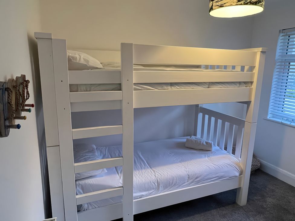 A bunk bed with white linens and a pillow at Greenbank in Woolacombe